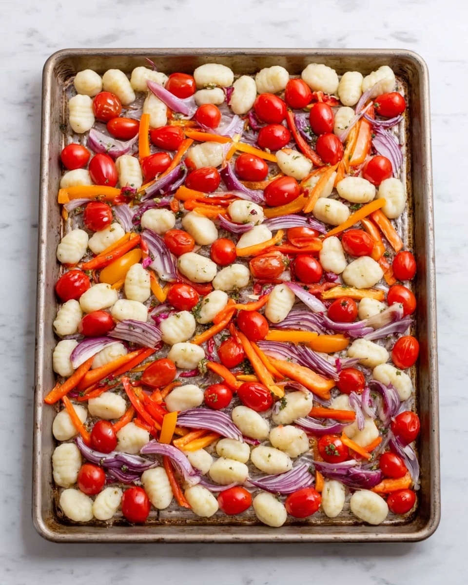 A baking tray filled with three main layers: the first layer is a spread of small white gnocchi evenly placed across the tray; the second layer consists of bright red cherry tomatoes scattered throughout; and the third layer is made up of thin strips of orange and red bell peppers mixed with pieces of purple red onion, all spread on top. The tray sits on a white marbled surface. photo taken with an iphone --ar 4:5 --v 7