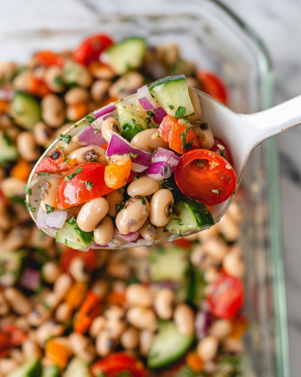 A white spoon holds a colorful scoop of bean salad above a clear glass dish filled with the same mix. The salad has a base layer of pale beige beans with small brown spots, mixed with bright red cherry tomato halves. Scattered throughout are chunks of green cucumber, small cubes of purple onion, and bits of orange and yellow bell pepper. There are also small green leaves of fresh herbs mixed evenly. The clear dish sits on a white marbled surface that adds a clean background to the vibrant salad. photo taken with an iphone --ar 4:5 --v 7