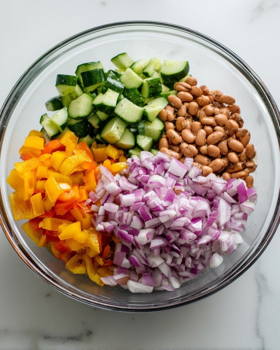 In a clear glass bowl, there are four separate layers of chopped ingredients. On the top left, there are bright green cucumber pieces with a fresh, crunchy texture. Next to it on the right, there is a layer of light brown beans with some darker spots, giving a soft and slightly shiny appearance. Below the beans, on the bottom right, there are small pieces of red onion, showing white and purple layers and a crisp texture. To the bottom left, there is a mix of orange and red bell pepper pieces, vibrant and slightly shiny. The bowl sits on a white marbled surface with soft natural light coming from the top. Photo taken with an iphone --ar 4:5 --v 7