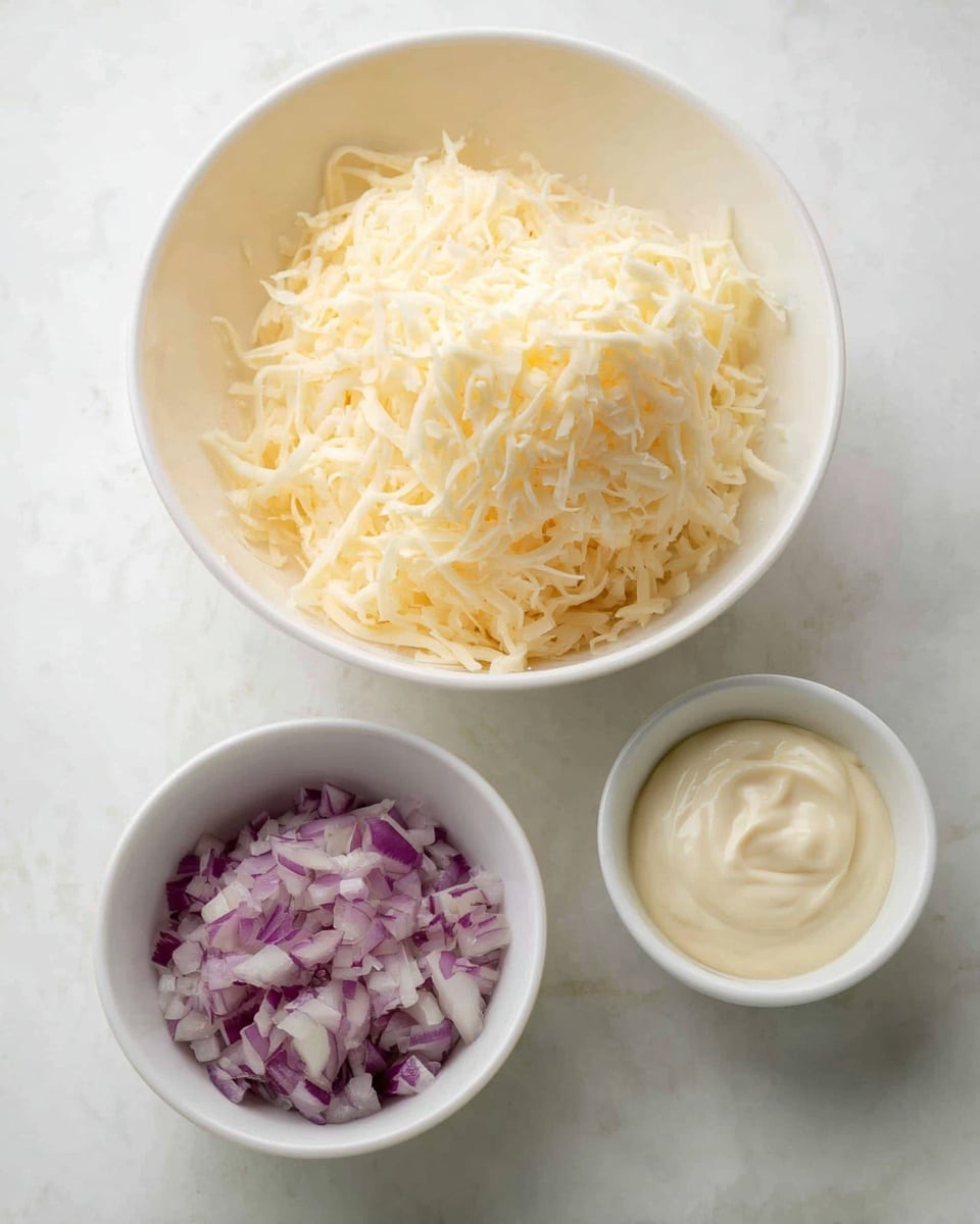 The image shows three white bowls on a white marbled surface. The largest bowl at the back is filled with a light yellow pile of finely shredded cheese with a soft texture. In the bottom left, there is a small white bowl filled with finely chopped purple and white onions, showing a mix of small uneven pieces. On the bottom right, another small white bowl holds a pale cream thick sauce or mayonnaise with a smooth and creamy texture. The overall look is clean and simple with soft lighting. Photo taken with an iphone --ar 4:5 --v 7
