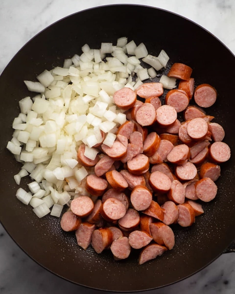 In a black pan, there are two main layers: one side has small white onion cubes that look fresh and slightly shiny, and the other side has sliced sausage pieces with a pinkish inside and a darker brown outer layer, arranged neatly without mixing. The pan surface is smooth and has a bit of shine from oil. The background is a white marbled texture. photo taken with an iphone --ar 4:5 --v 7
