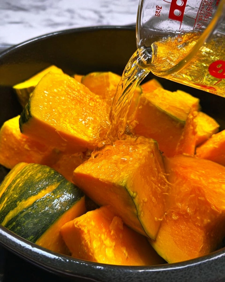 The image shows large chunks of bright orange pumpkin with green skin in a black pot. A clear liquid is being poured from a glass measuring cup into the pot, splashing slightly on the pumpkin pieces. The pumpkin chunks have rough, uneven surfaces and are stacked in the pot. The background is a white marbled surface. photo taken with an iphone --ar 4:5 --v 7