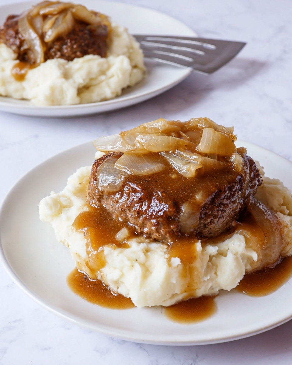 The image shows two layers of food on a white plate with a white marbled background. The bottom layer is creamy mashed potatoes with a soft, slightly lumpy texture in white color. On top of the mashed potatoes is a thick, dark brown cooked meat patty, covered with a glossy brown gravy. The gravy also has cooked, translucent, golden-brown onion slices spread on top of the meat and spilling slightly onto the mashed potatoes. In the background, another white plate with a similar arrangement is partially visible. Photo taken with an iphone --ar 4:5 --v 7