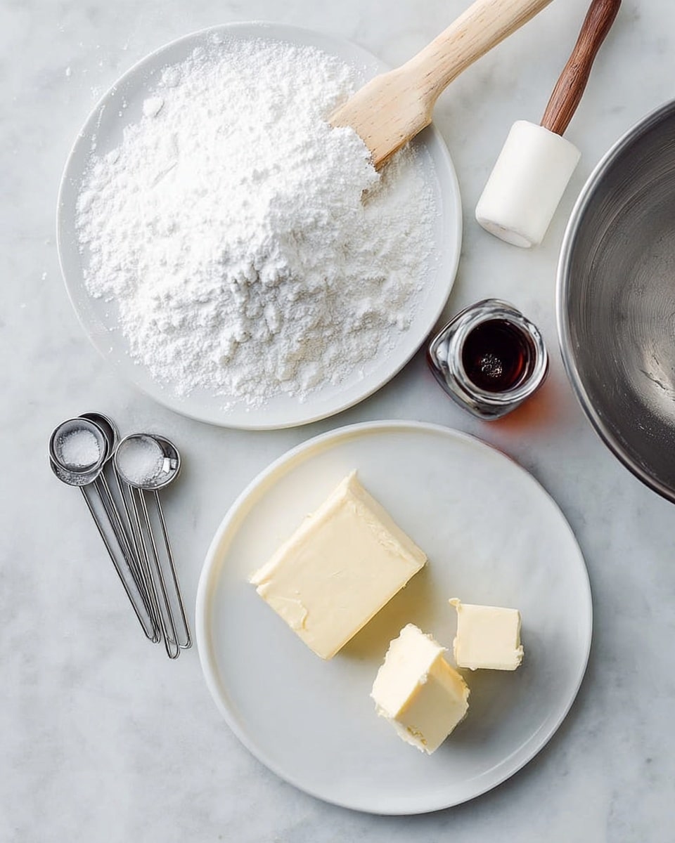 A white round plate holds two rectangular blocks of cream cheese and two square pats of butter, all pale and smooth, placed slightly apart. Below the plate is a second white round plate filled with a fine pile of white powdered sugar, fluffy in texture and slightly mounded. To the left, several metal measuring spoons are arranged in a loose stack on the white marbled surface. Above the plates, a small clear glass bottle filled with dark brown vanilla extract sits, its opening facing upward with the cap removed. A wooden spatula with a white silicone head rests diagonally from the top left corner. On the right edge, part of a silver metal mixing bowl with a handle is partially visible. The whole scene is set on a white marbled textured surface. photo taken with an iphone --ar 4:5 --v 7
