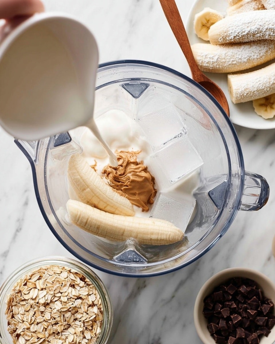 The image shows a clear blender container filled with layers from bottom to top: ice cubes with a smooth, translucent texture, peeled bananas lying flat with a soft, pale yellow color, a thick dollop of light brown peanut butter, and white yogurt with creamy texture partially covering the banana. A woman's hand is pouring white milk from a white pitcher into the blender. Surrounding the blender is a white marbled surface with a glass dish holding three peeled bananas dusted with white powder in the top right corner, a white bowl filled with rolled oats with a wooden spoon in the bottom left, and a small glass jar containing dark brown chocolate chips near the right edge. photo taken with an iphone --ar 4:5 --v 7