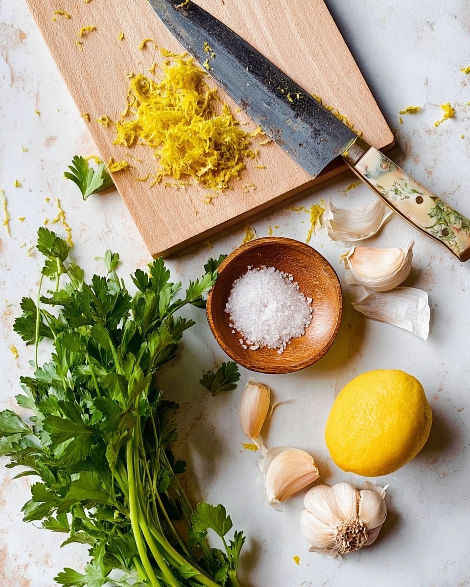 The image shows a light wooden cutting board with some yellow lemon zest on it and a large knife with a worn blade resting on top. Below the cutting board on a white marbled surface are three garlic cloves, some loose garlic skin, a small round wooden dish filled with white coarse salt, a large fresh bunch of green parsley with long stems, and a lemon with large pieces of peel partially removed and lying nearby. The whole scene displays fresh ingredients for cooking arranged naturally. Photo taken with an iphone --ar 4:5 --v 7