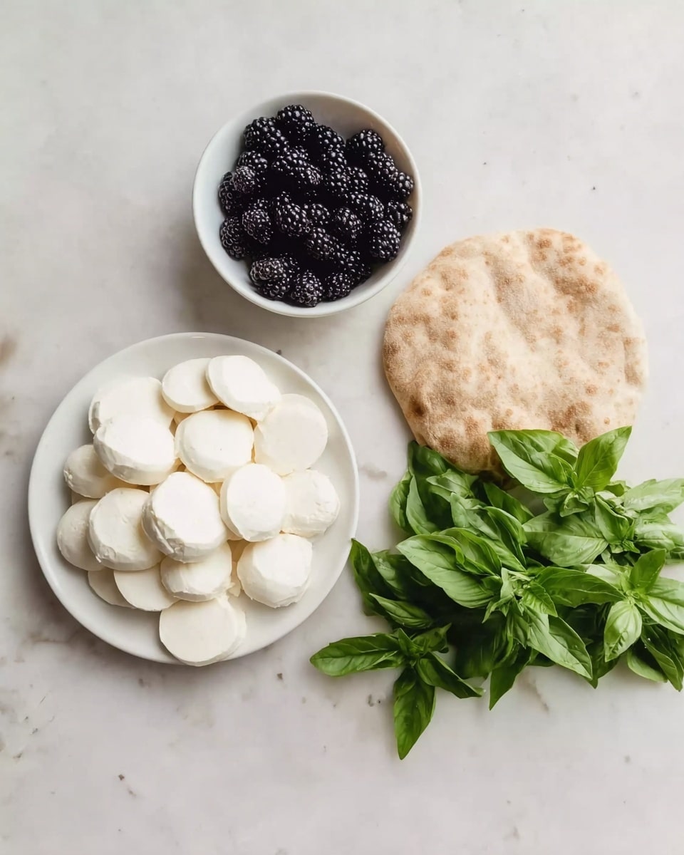 The image shows three main food items neatly placed on a white marbled surface. On the left, there is a white plate full of round white cheese slices arranged in a loose pile. To the top left, there is a small white bowl filled with shiny blackberries. On the right side, there is a round, light brown flatbread next to a bunch of bright green fresh basil leaves. The colors are soft and natural, with the white cheese and the flatbread contrasting against the dark blackberries and the vibrant green leaves. photo taken with an iphone --ar 4:5 --v 7