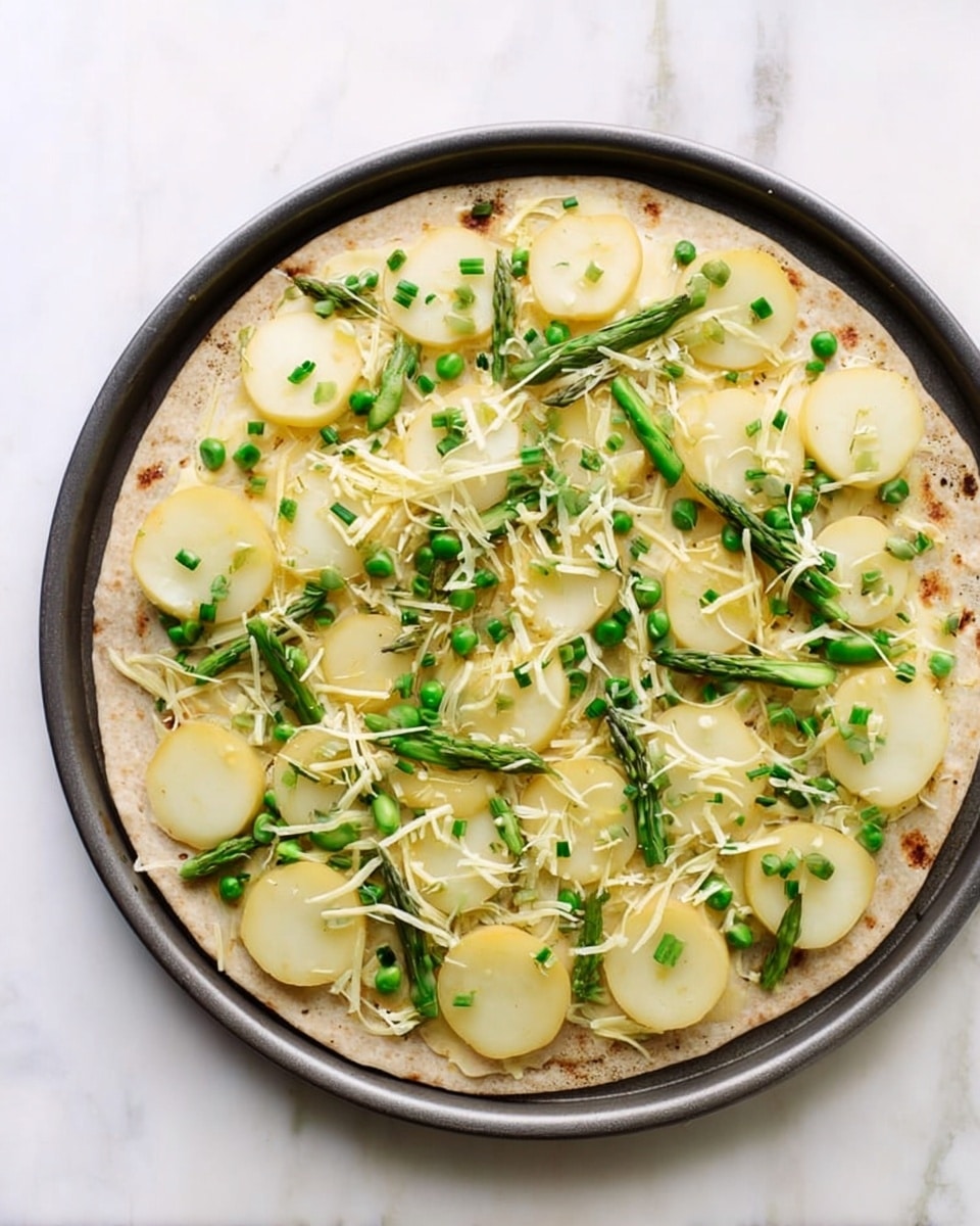 A round flatbread is laid flat in a dark round pan on a white marbled surface. The flatbread forms the base layer, light brown with some darker spots. The second layer consists of thin slices of light yellow potato, evenly spread across the flatbread in a circular pattern with some overlap. The third layer has a light scattering of shredded pale yellow cheese sprinkled over the potatoes. The top layer is small round slices of bright green asparagus, evenly spread on top along with finely chopped green chives scattered all over. The overall look is fresh and colorful with layers clearly visible. photo taken with an iphone --ar 4:5 --v 7