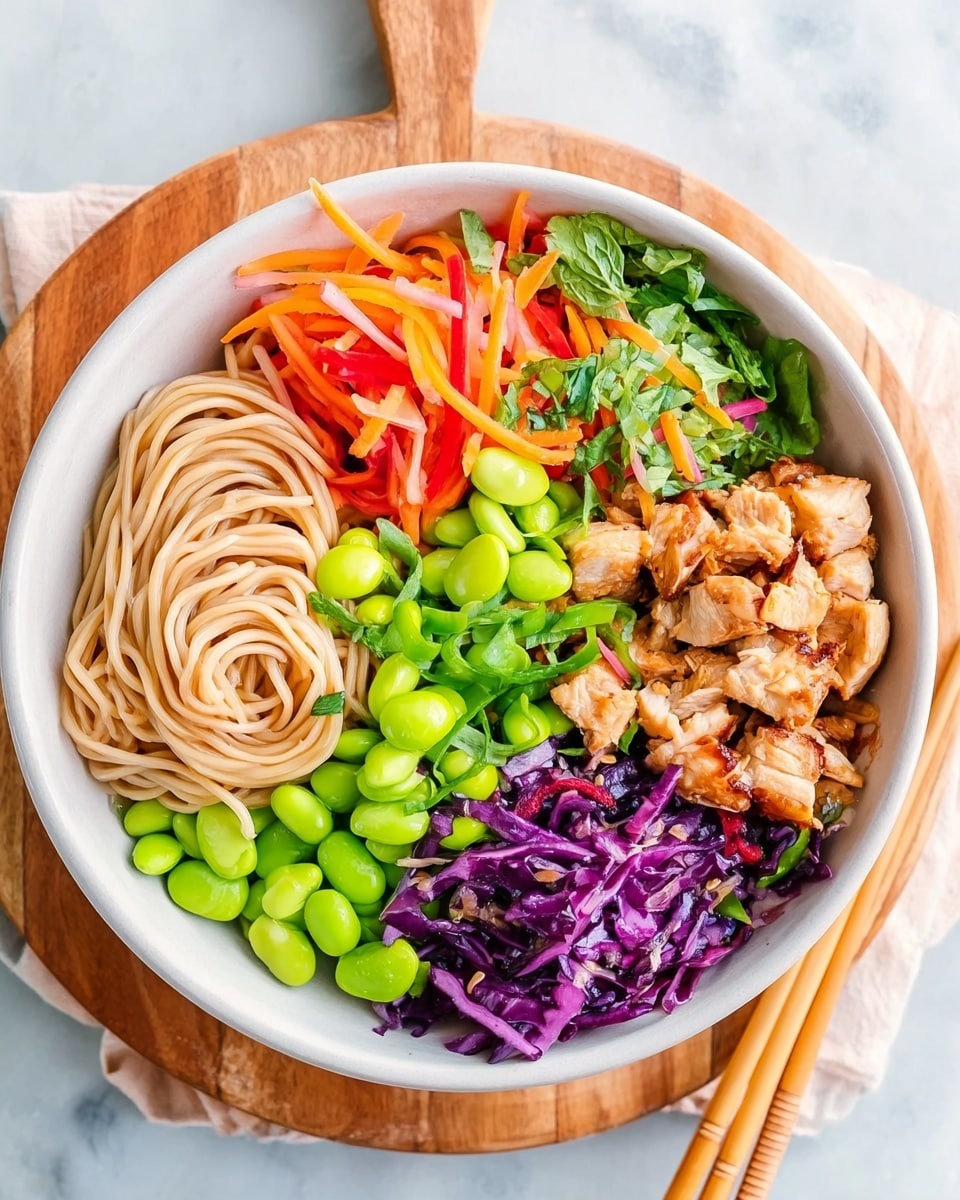 A white bowl filled with four distinct sections: in the bottom left, light brown thin noodles softly piled; next to it on the right, a heap of bright green edamame beans layered on top and around small chunks of golden-brown cooked chicken pieces; the top right quarter contains mixed fresh vegetables, including thin strips of red bell pepper, orange carrot, green leafy herbs, and purple cabbage shreds; all the ingredients look fresh and evenly layered. The bowl sits on a wooden board, over a white marbled surface, with a pair of chopsticks resting nearby. Photo taken with an iphone --ar 4:5 --v 7
